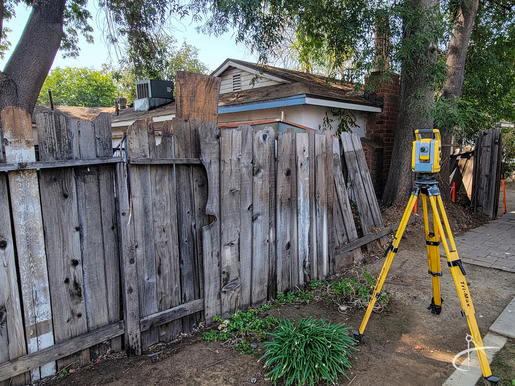 Survey total station next to an aging fence.