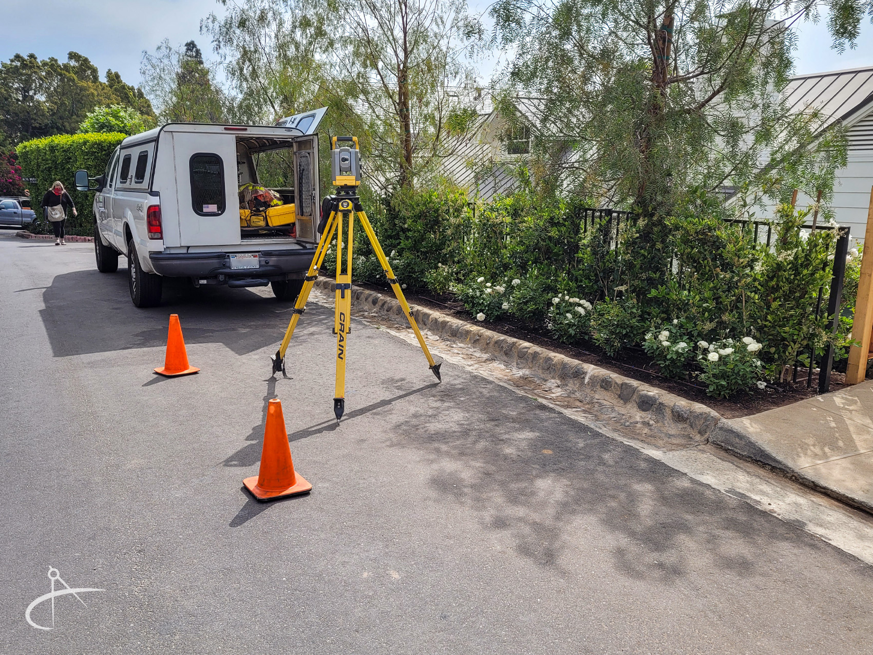 Total station surveying instrument setup next to work truck.